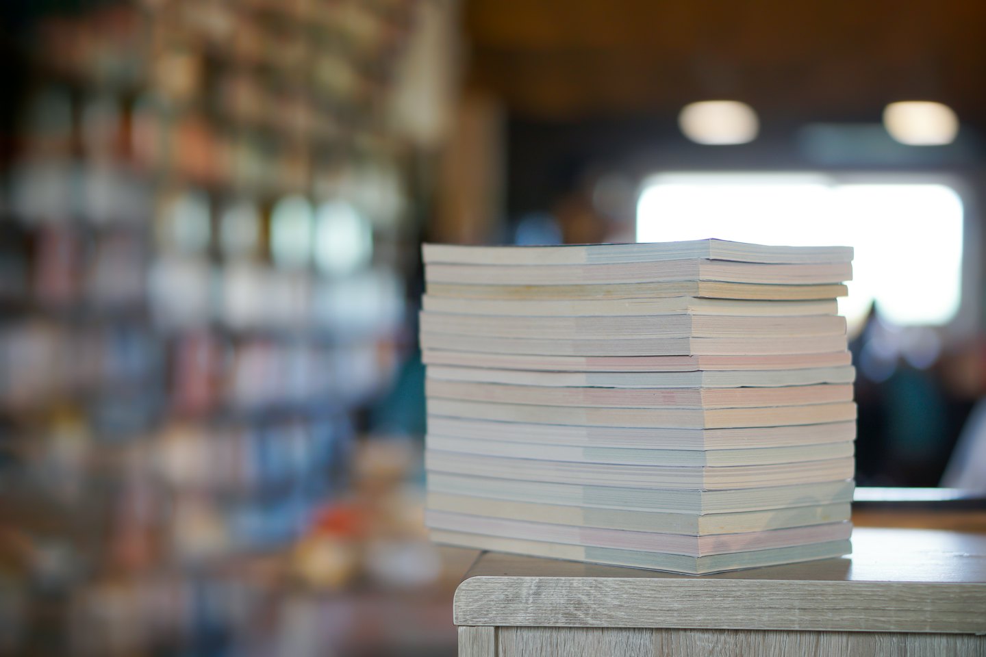 Una pila de libros finos descansa sobre una mesa de madera.