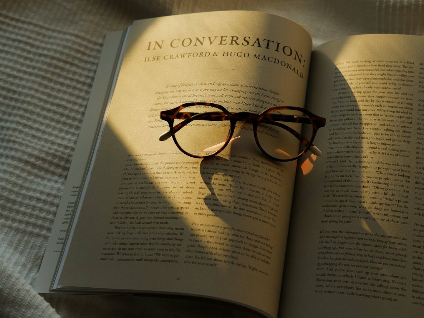 Unas gafas de carey descansan sobre un libro abierto en una tela texturizada.